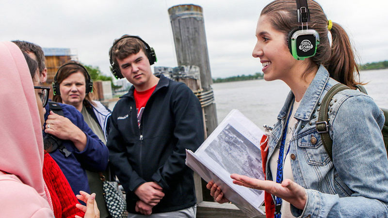 tour guide and group in Silent Sound System headphones near a bay