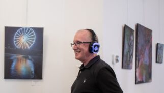 A man smiles while listening to a guided tour using Silent Sound System headphones in an art gallery