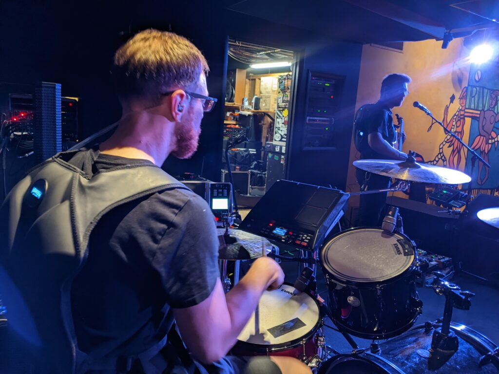 BASSpak On Stage Monitoring A drummer and bassist wearing BASSpak to monitor their live sound