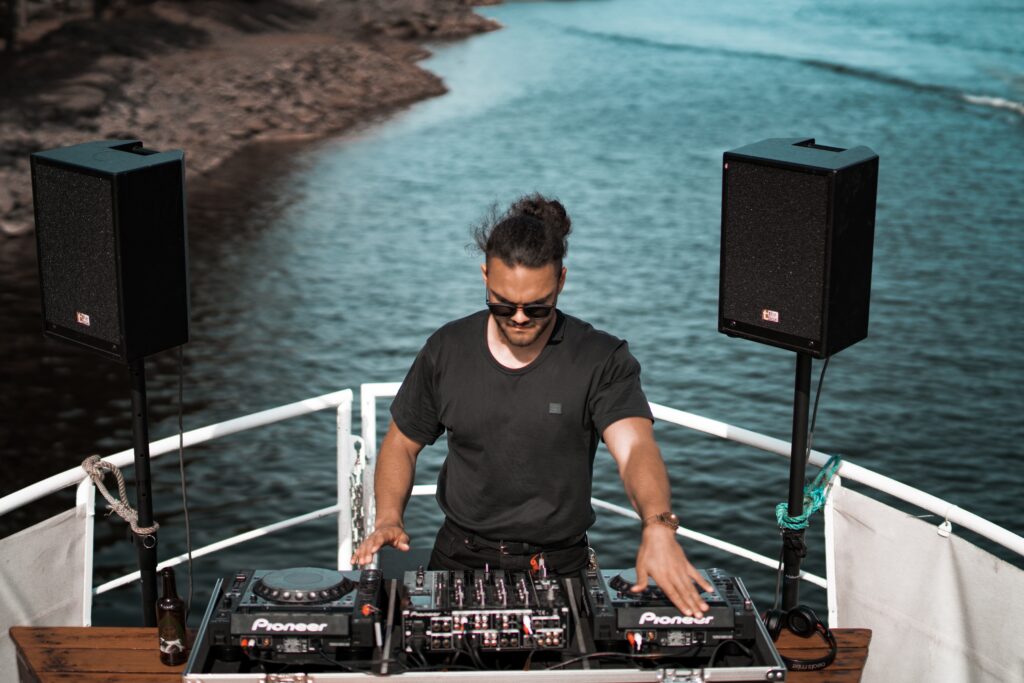 Man DJing on a boat with speakers next to him.